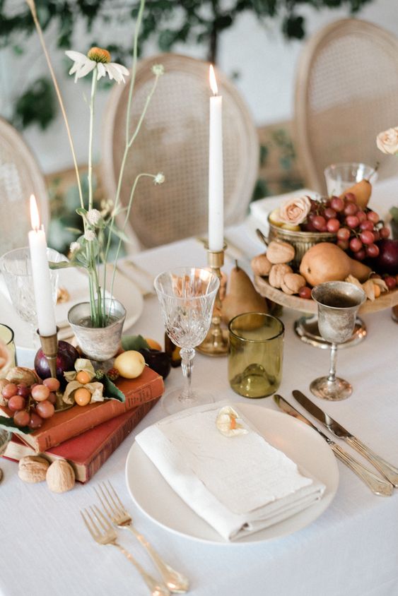 a harvest wedding tablescape with vintage books, fruit, berries, pears, roses and some candles is a very refined idea for the fall