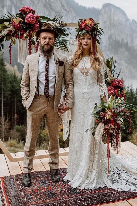 a hippie groom with a neutral printed suit, a white shirt, a printed tie, brown shoes and a brown hat