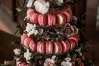a hot pink macaron tower with white blooms, greenery and berries is a cool idea for a bright pink modern wedding