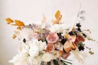 a jaw-dropping delicate-colored fall wedding bouquet of white, pink, rust blooms and fall-colored leaves and ribbons is very chic