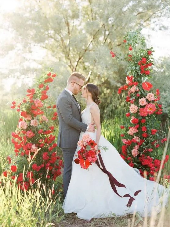 a lovely and refined Valentine's Day wedding altar with red and blush roses and greenery looks extremely romantic and very chic