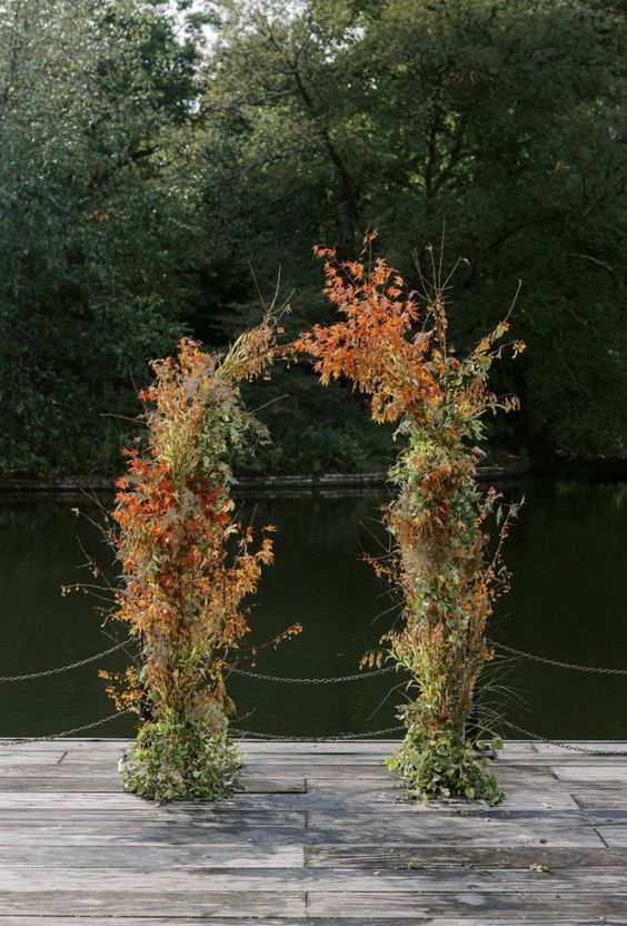 a lush and textural fall wedding arch covered with greenery and bold leaves is a cool idea for a natural fall wedding