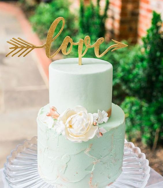 a mint green wedding cake with a textural tier, a calligraphy topper and white sugar blooms