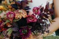 a moody fall wedding bouquet of pink and burgundy blooms, dark foliage and mustard ribbon is wow