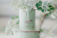 a naked mint green wedding cake topped with fresh blooms and greenery and a sheer monochromatic touch