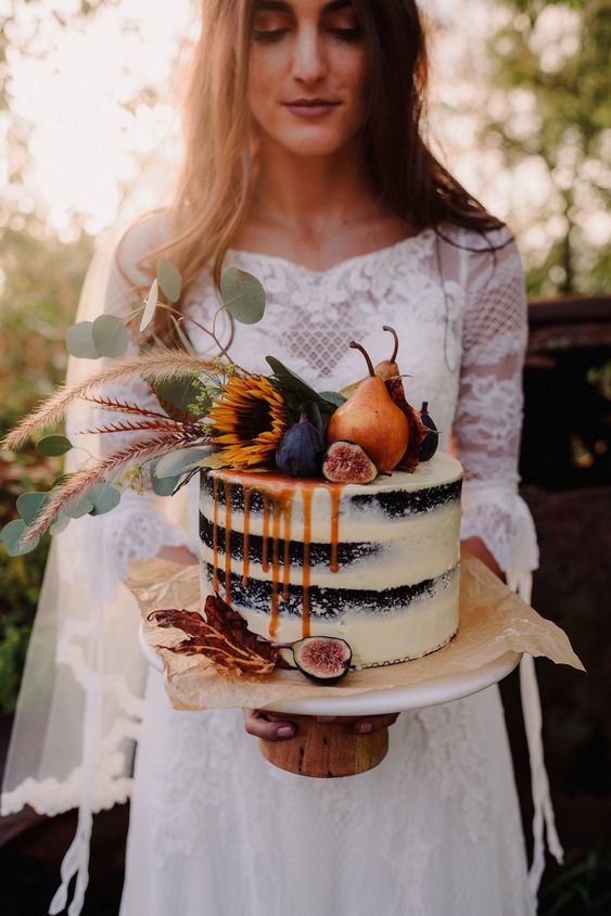 a naked wedding cake with caramel drip, figs, pears, greenery and sunflowers on top is a fantastic boho fall wedding