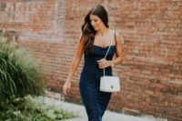 a navy cocktail midi dress with spaghetti straps, white shoes and a white small bag