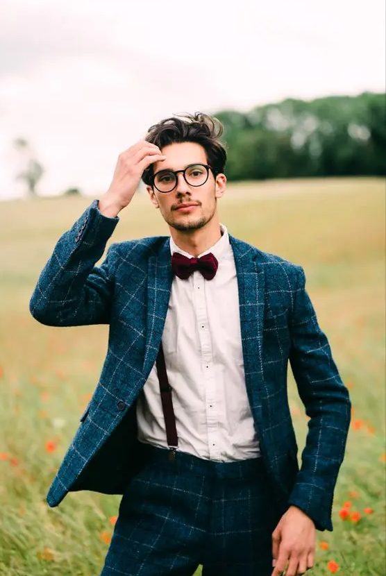 a navy groom plaid suit, a white shirt, black suspenders, a burgundy bow tie and black frame glasses are an awesome combo