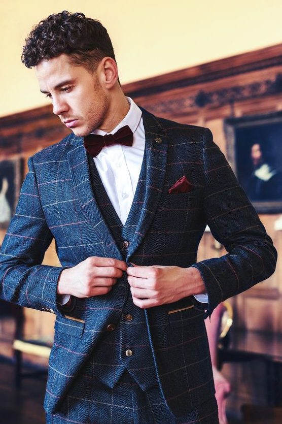 a navy windowpane print three-piece suit, a white shirt, a burgundy velvet bow tie and a matching handkerchief