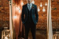 a navy windowpane print three-piece suit, a white shirt, a printed tie and brown shoes for a vintage-inspired groom’s look