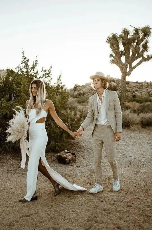 a neutral boho groom's look with a greige windowpane suit, a white shirt, white trainers and a hat is great for a desert wedding