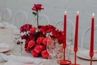 a neutral wedding tablescape with a tan tablecloth, white napkins, two-tone menues and a lush red floral centerpiece plus bold red candles