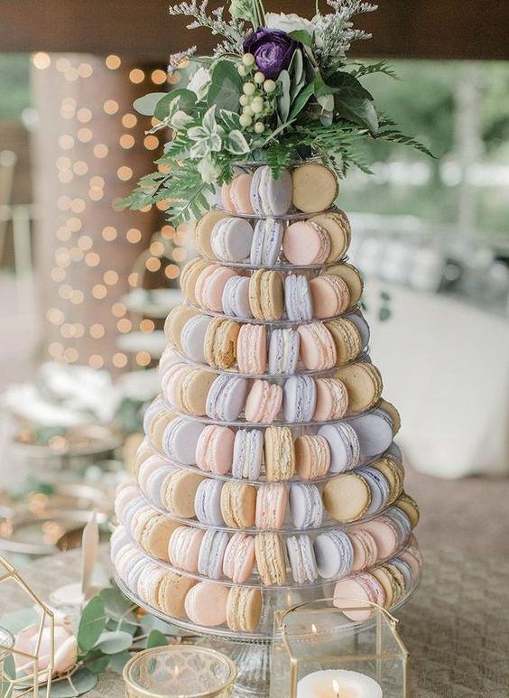 a pastel macaron tower with blush, blue and tan macarons, a purple bloom and greenery plus berries is a chic idea
