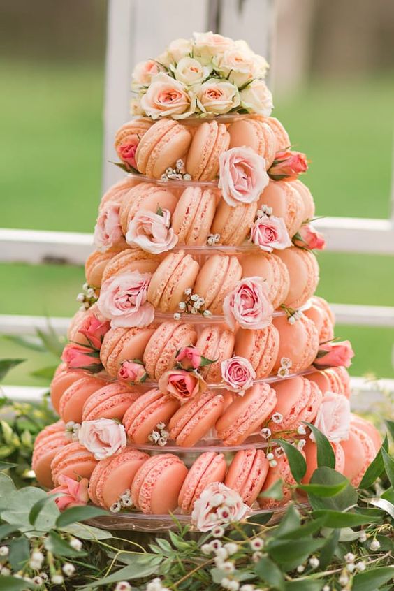 a pink macaron tower with a clear stand, light pink blooms and neutral ones is a beautiful idea for a pastel wedding