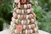 a pretty macaron tower with pink, blush, brown and emerald macarons, pink blooms, a white wedding cake with pink and burgundy blooms