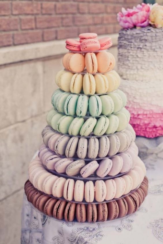 a rainbow-colored macaron tower with pink, orange, yellow, various green, lavender and brown macarons is a very fresh and bold idea