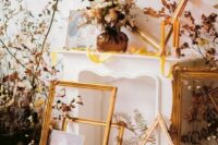 a refined fall wedding backdrop of a faux fireplace, empty frames, fall leaves, candles and a floral arrangement is a gorgeous idea
