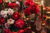 a refined modern Valentine’s Day table with blush and red roses, gold candleholders, chargers and cutlery and chic crystal glasses