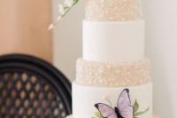 a refined wedding cake with white and neutral pearl tiers, with sugar blooms and leaves and a purple butterfly is gorgeous