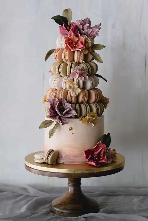 a refined wedding dessert composed of an ombre wedding cake and a pastel macaron tower, pastel blooms and foliage is amazing