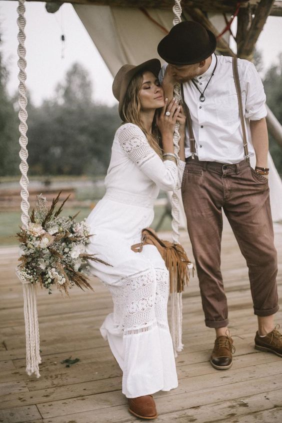 a relaxed boho groom's look with brown pants and shoes with no socks, brown suspenders and a black hat