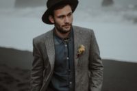 a relaxed groom’s look with a grey jacket, a slate grey shirt, black pants, a black hat plus a bolo tie