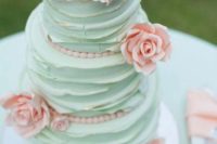 a romantic mint green wedding cake decorated with pink beads and pink sugar blooms