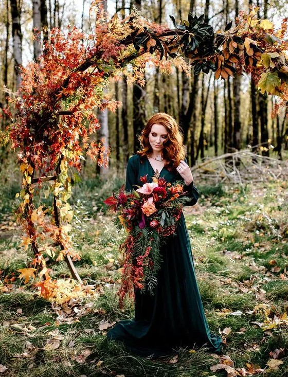a round wedding arch decorated with colorful fall leaves and magnolia leaves for a woodland fall wedding