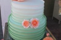 a ruffled ombre wedding cake from white to mint green topped with sugar coral blooms