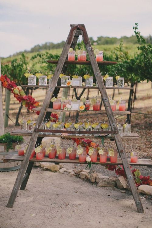 a rustic wedding bar of a large ladder, lots of drinks and soem blooms is a very cool and stylish piece