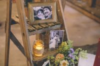 a rustic wedding decoration of a ladder, bright blooms and greenery, candles and family photos in frames