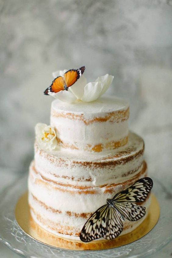a semi naked wedding cake decorated with white blooms and faux butterflies is a cute and fairy tale like piece