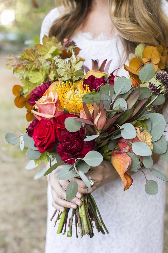 a simple and bright fall wedding bouquet of greenery, fall elaves, yellow, pink and burgundy blooms is amazing