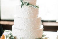 a simple white textural buttercream wedding cake with greenery and pears on top is a stylish idea for the fall