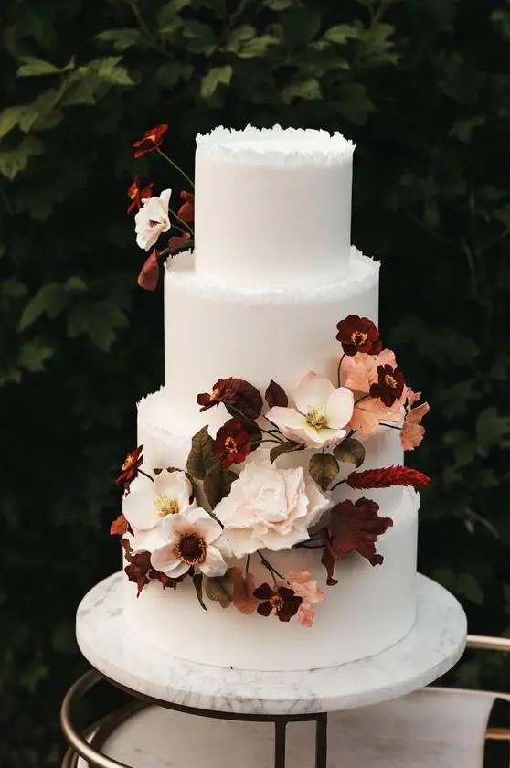 a sophisticated modern fall wedding cake with a rough edge, beautiful blush, burgundy blooms and bold foliage is amazing