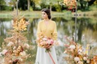 a sophisticated modern wedding arch with bright fall leaves, blush, white and mustard blooms and a gorgeous lake view is wow
