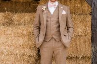 a striped brown three-piece tweed suit, a white shirt, a blush bow tie and brown shoes for a rustic wedding