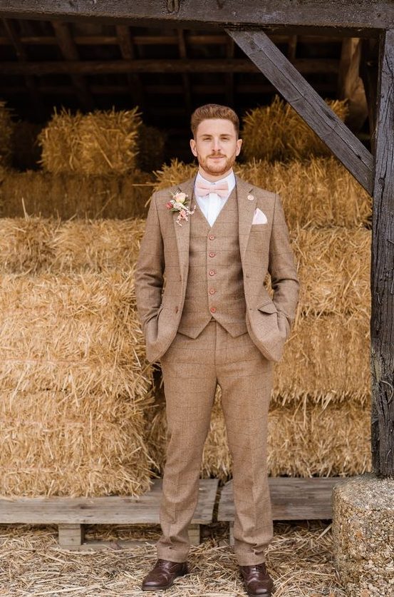 a striped brown three-piece tweed suit, a white shirt, a blush bow tie and brown shoes for a rustic wedding