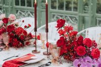 a stylish and chic vintage wedding tablescape with lush red and blush florals, deep red candles and red napkins strikes with color