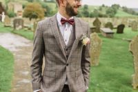 a stylish checked beige three-piece suit, a white shirt with copper buttons, a burgundy bow tie