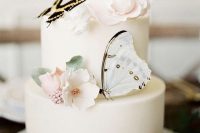 a stylish white wedding cake with sugar blooms and leaves and a couple of beautiful butterflies is amazing