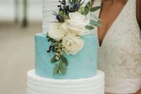 a textural wedding cake with white and tiffany blue tiers, fresh white blooms, thistles and greenery