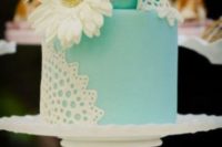 a tiffany blue wedding cake decorated with white sugar lace and a large white fresh bloom