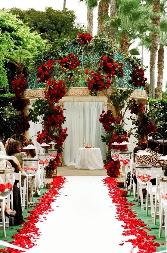 a wedding altar done with red roses, greenery and red rose petals on the floor is a fantastic idea for Valentine's Day