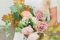 a wedding bouquet of pink roses and fall leaves of a unique and creative shape