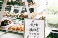 a wedding dessert station of a white ladder, greenery and desserts of various kinds is a very cool idea