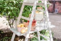 a wedding drink station of a white ladder, a chalkboard and potted greenery