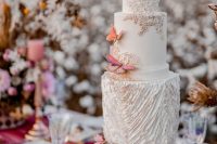 a whimsical wedding cake done in grey and white, with plenty of texture and pink and orange butterflies is a lovely and bold idea