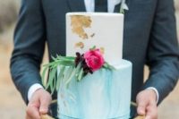 a white and watercolor tiffany blue wedding cake decorated with gold leaf, greenery and bright blooms