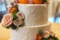 a white buttercream wedding cake with a texture, sugar pumpkins, pink and blush blooms and greenery is all cool